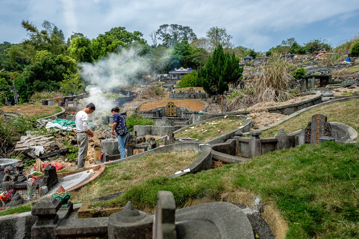 A couple burns spirit money for his father at the graveside in observance of Qingming. (Photo: Naomi Hellman)