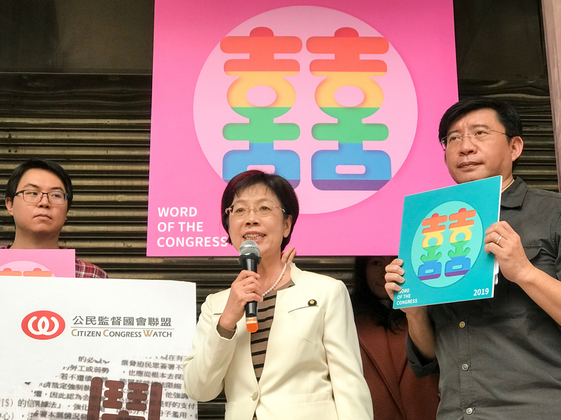 Yu Meinu (centre) à une conférence de presse le 30 décembre 2019, quelques mois après la légalisation du mariage entre personnes du même sexe, pour dévoiler le caractère choisi pour résumer l'année au Parlement : Le double xi, symbole du mariage, aux couleurs du drapeau LGBT (photo CNA)