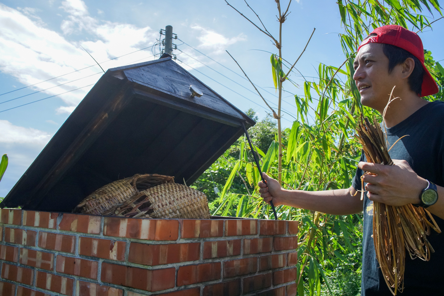 Akac Orat devant le four qui permet de fumer les paniers en rotin qu'il a tissés avec ses stagiaires (photo : Sasa)