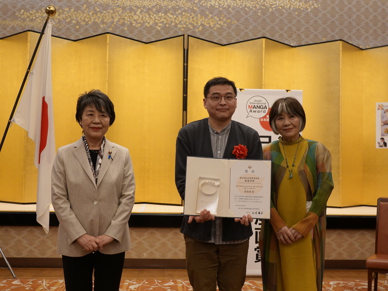 Jason Chien reçoit la récompense des mains de la ministre japonais des Affaires étrangères Yōko Kamikawa (à g.) et de la présidente du jury Machiko Satonaka (à d.) (photo CNA)