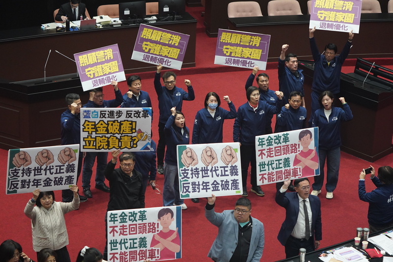 Les députés du KMT et du DPP brandissant au Yuan législatif des pancartes pour et contre l'augmentation du taux de remplacement des pensions de retraite des policiers (photo : CNA)