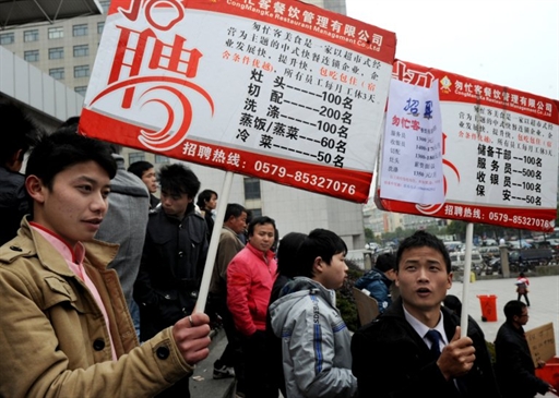 中國大陸近來出現農民工短缺問題，圖為浙江義烏的招聘人員舉牌尋人。(AFP)