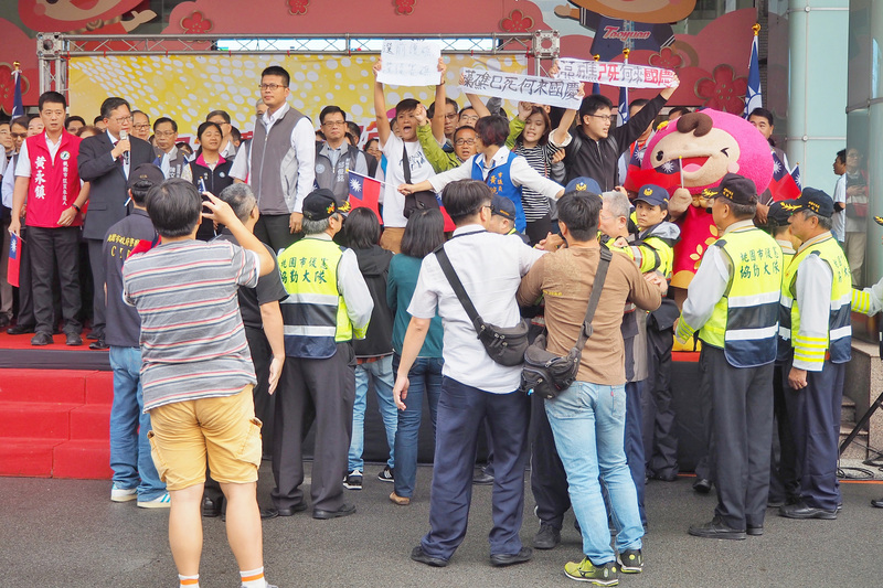 桃園市政府10日舉行改制後首次自辦國慶升旗典禮，桃園市長鄭文燦（前排左2）致詞時，無黨籍桃園市長參選人朱梅雪突率藻礁保護團體上台抗議。<br />(圖：中央社)