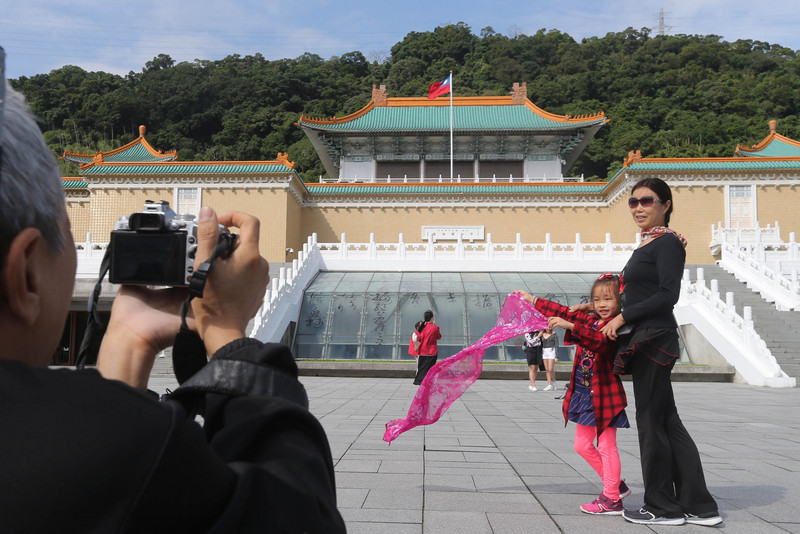 故宮13日臨時召開記者會表示，依去年行政院核定版「新故宮計畫」沒有說要閉館整建，會朝向不閉館同時進行整擴建。圖為觀光客在故宮北院外拍照留念。(圖：中央社)