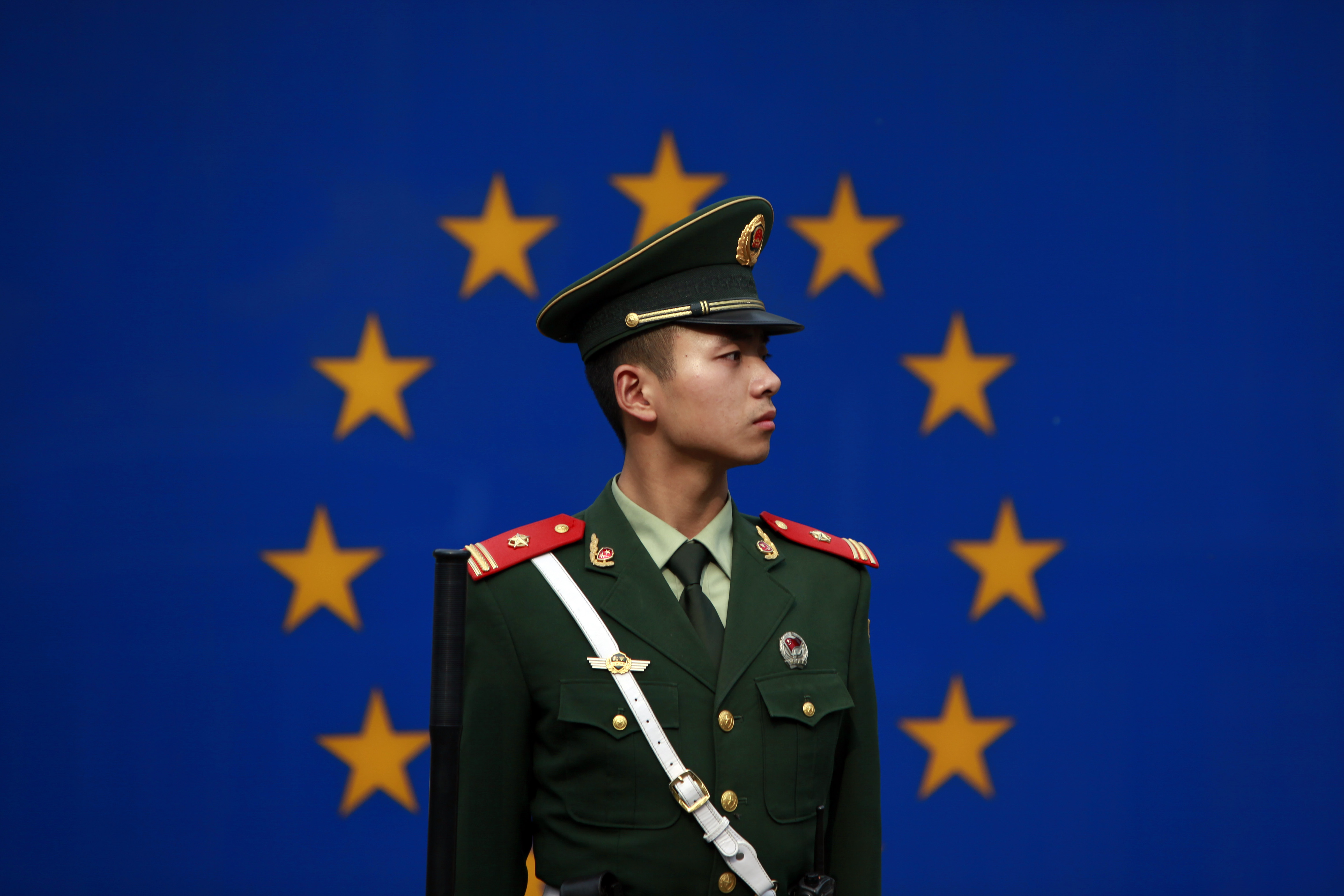 德國將推動歐盟對中國採更強硬立場。圖為一名中國警察站在歐盟駐華代表團辦公室外的歐盟旗幟前。 (美聯社/達志影像)
