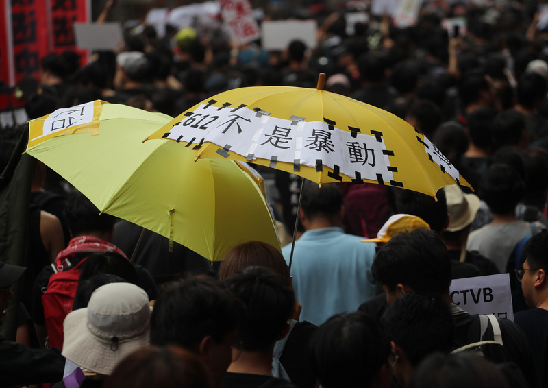 圖為香港泛民主派團體民間人權陣線2019年6月16日再次發起反修訂逃犯條例大遊行，遊行隊伍中有民眾在雨傘貼上「612不是暴動」表達訴求。(資料照片/CNA)