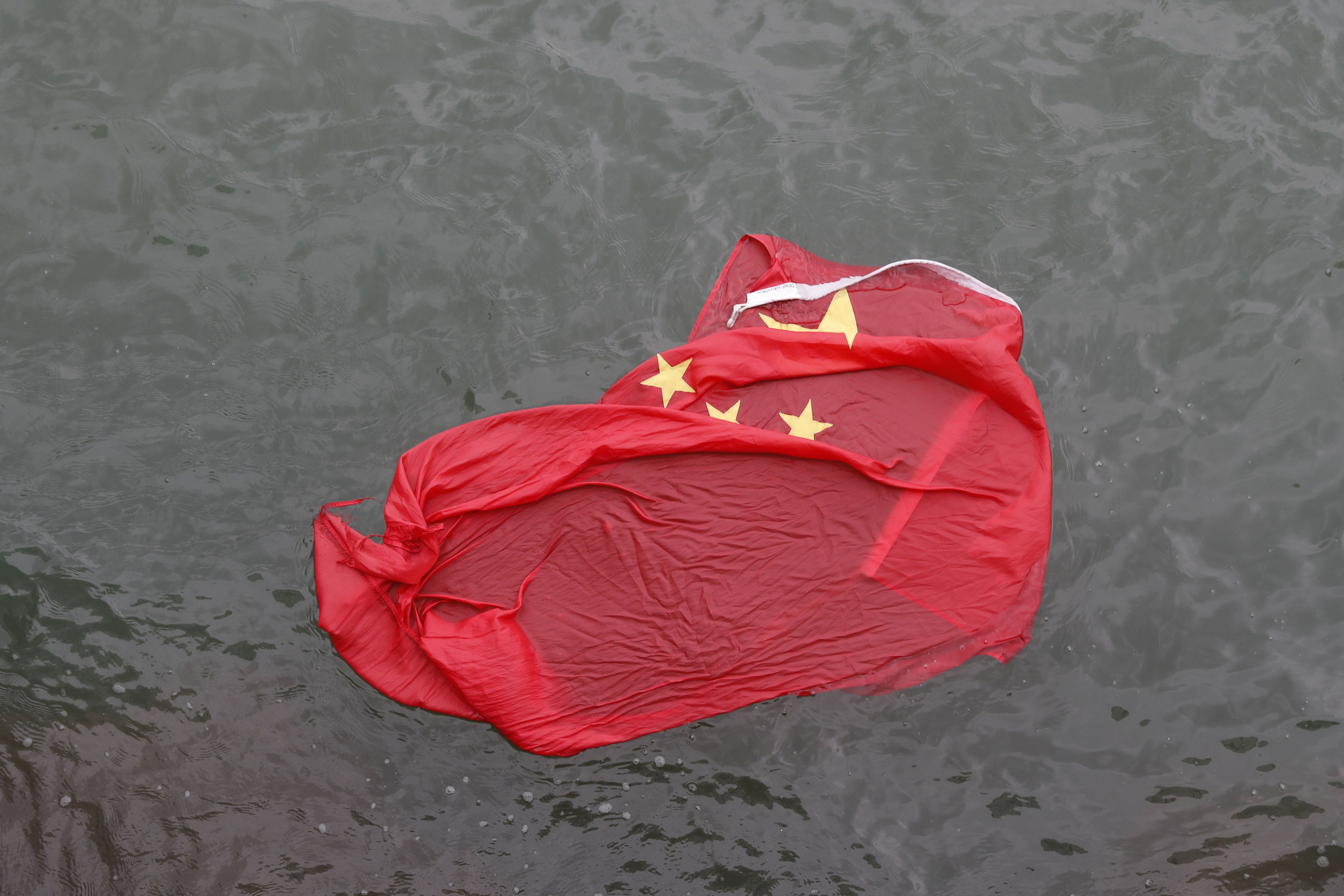 香港反送中抗爭，示威民眾將中國五星旗拋丟入海。(美聯社/達志影像)
