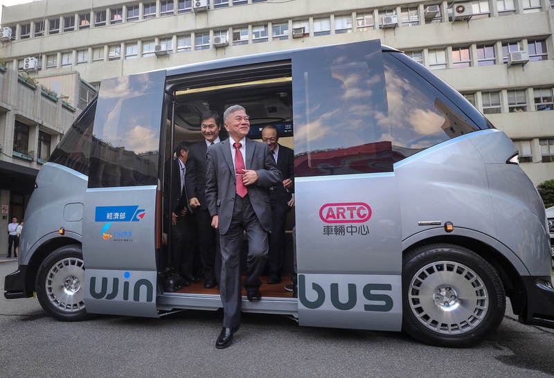 財團法人車輛研究測試中心串連產業打造台灣自研自製的自駕電動小型巴士WinBus，26日在經濟部亮相，經濟部長沈榮津（前中）出席見證並試乘。(圖：中央社)