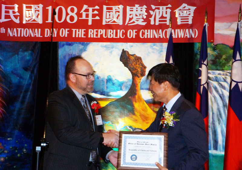 駐舊金山台北經濟文化辦事處處長馬鍾麟在7日的雙十國慶酒會，接受內華達州政界代表史都華的祝賀，舞台背景是旅美畫家牟宗瑋創作的台灣意象鄉情畫。(圖：中央社)