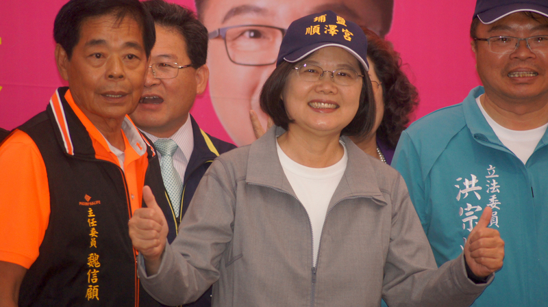 總統蔡英文16日到彰化埔鹽鄉順澤宮上香，廟方贈送因挪威三鐵選手艾登戴著奪冠爆紅的「冠軍帽」，蔡總統戴上帽子、比出手勢，跟民眾一起合影留念。(圖：中央社)
