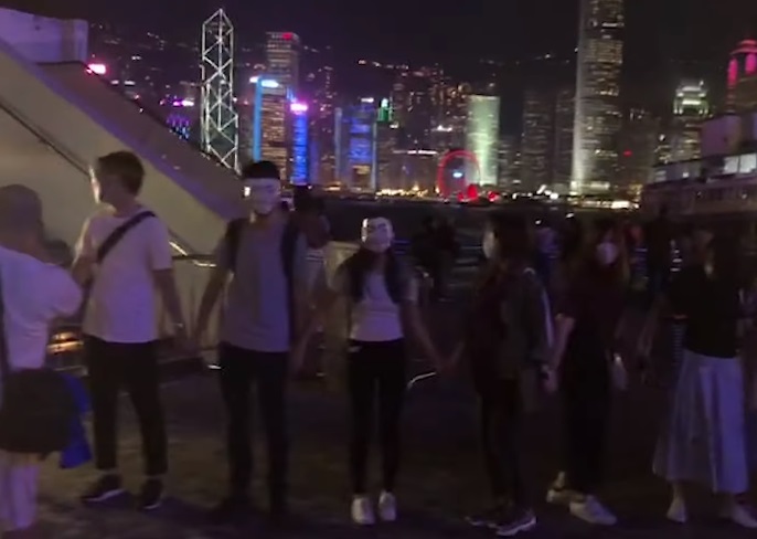 香港網民發起各區面具人鏈活動，參與者戴上不同圖案的面具。(圖擷自YouTube)