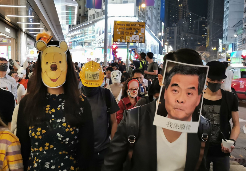 香港「反送中」網友趁著31日西洋萬聖節之際在晚間發起集會遊行，並載著各式造型面具。(圖：中央社)