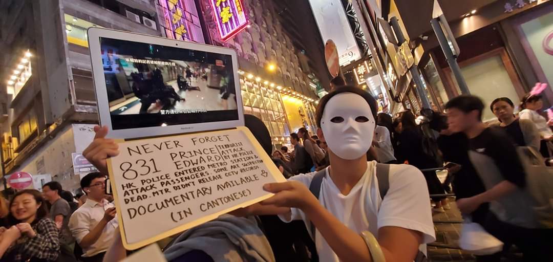 萬聖節夜晚，香港蘭桂坊擠滿人潮，蒙面者手持標語，呼籲勿忘831港警在太子地鐵站的暴行。(香港前記協主席岑倚蘭攝)