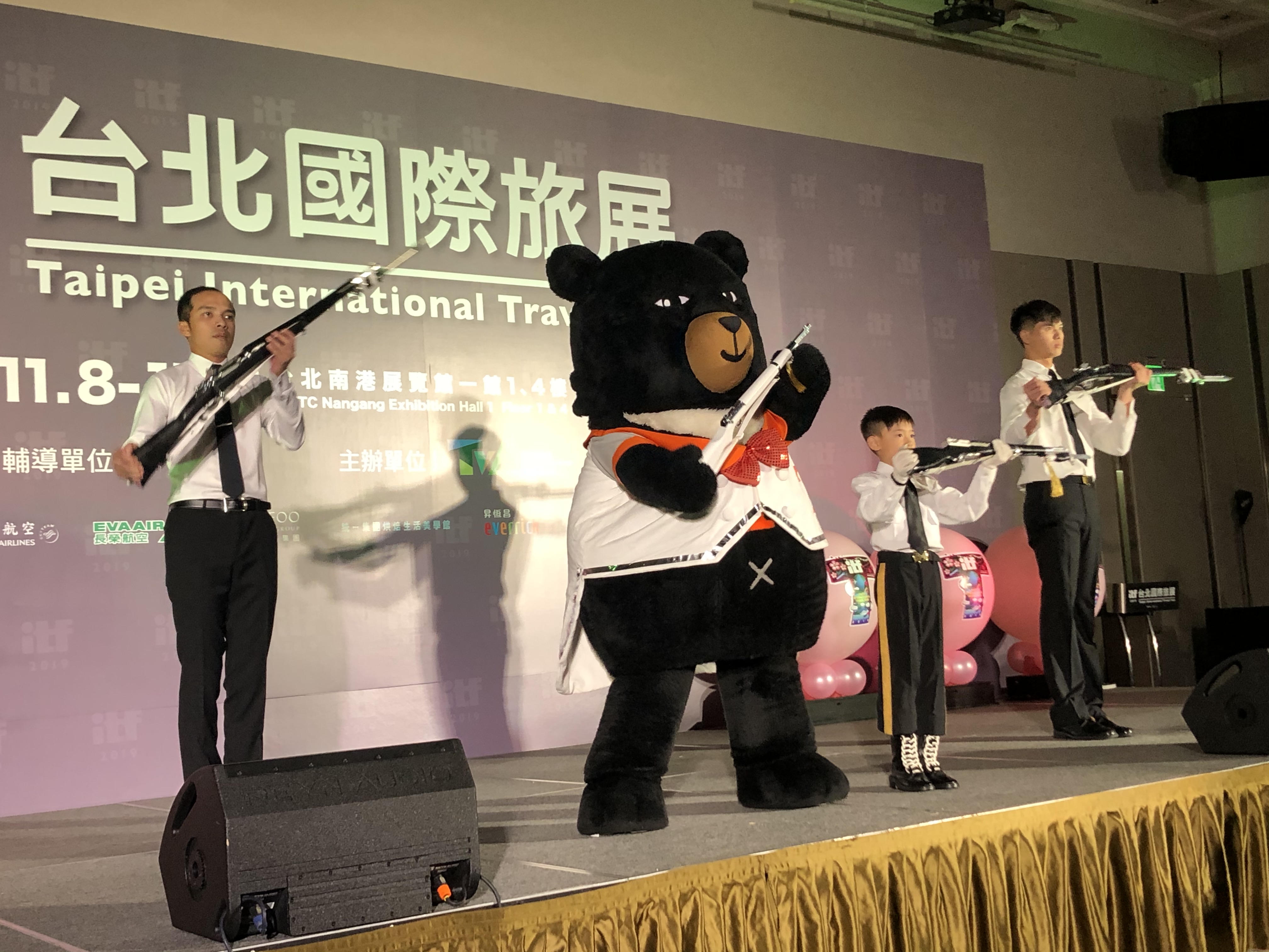 觀光局超級任務組喔熊組長在「2019台北國際旅展ITF」展前記者會開場表演上，加入特技槍法炫技行列，展現罕見的英姿。(吳琍君 攝)