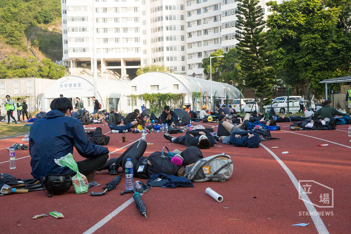 香港教育局13日稍早宣布，全香港14日停課之後，有些學生家長認為，教育局的停課安排無法解決根源問題，政府應解決政治紛爭。圖為中大學生為守護校園在操場就地休息。（立場新聞）