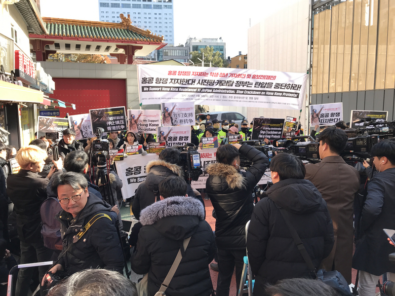 韓國大學生們19日上午在首爾明洞中國駐韓大使館正門前，高舉著「支持香港抗爭！習近平和林鄭月娥立即停止鎮壓」的標語，抗議中國政府對香港示威的暴力鎮壓。(圖:中央社)