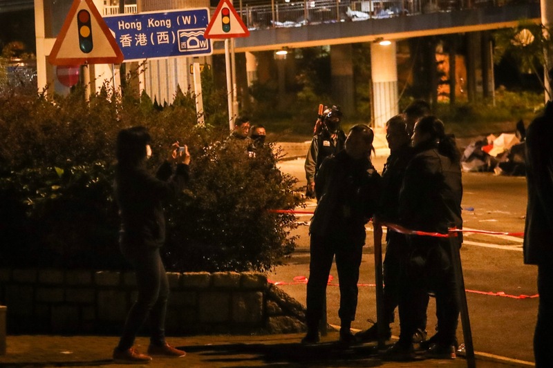 近來反送中爆發激烈警民衝突，警方從11月18日起包圍香港理工大學，並在校區外設防線，20日凌晨有警務人員在防線外拍照留念。(圖：中央社)
