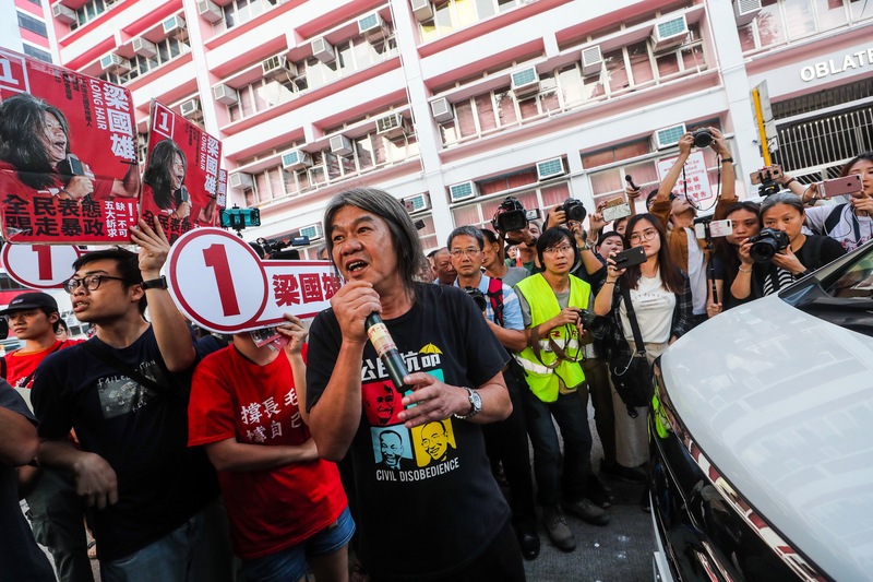 香港近日抗爭情勢逐漸趨緩，24日區議會選舉如期舉行，民建聯主席李慧琼原先預計下午受訪，社民連梁國雄（中）現身並攔阻座車。(中央社)
