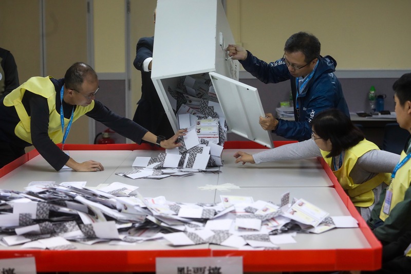香港近日抗爭情勢逐漸趨緩，24日區議會選舉如期舉行，晚間10時30分結束投票後進行點票作業，灣仔一家投票站工作人員將選票倒入點票檯上。(圖:中央社)