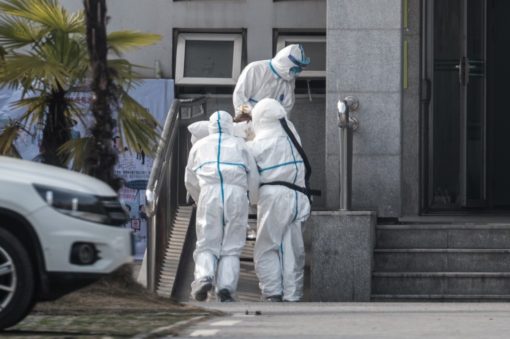 圖為武漢市醫護人員1月18日將一名病患送進醫院。(AFP)