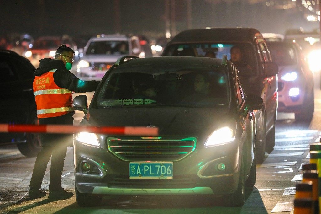 武漢肺炎疫情迅速蔓延，武漢官方下令封城、市民強制戴口罩，不少人趕在禁令生效前連夜逃出武漢。圖為檢疫人員在高速公路出口處強制量測民眾體溫。(AFP)