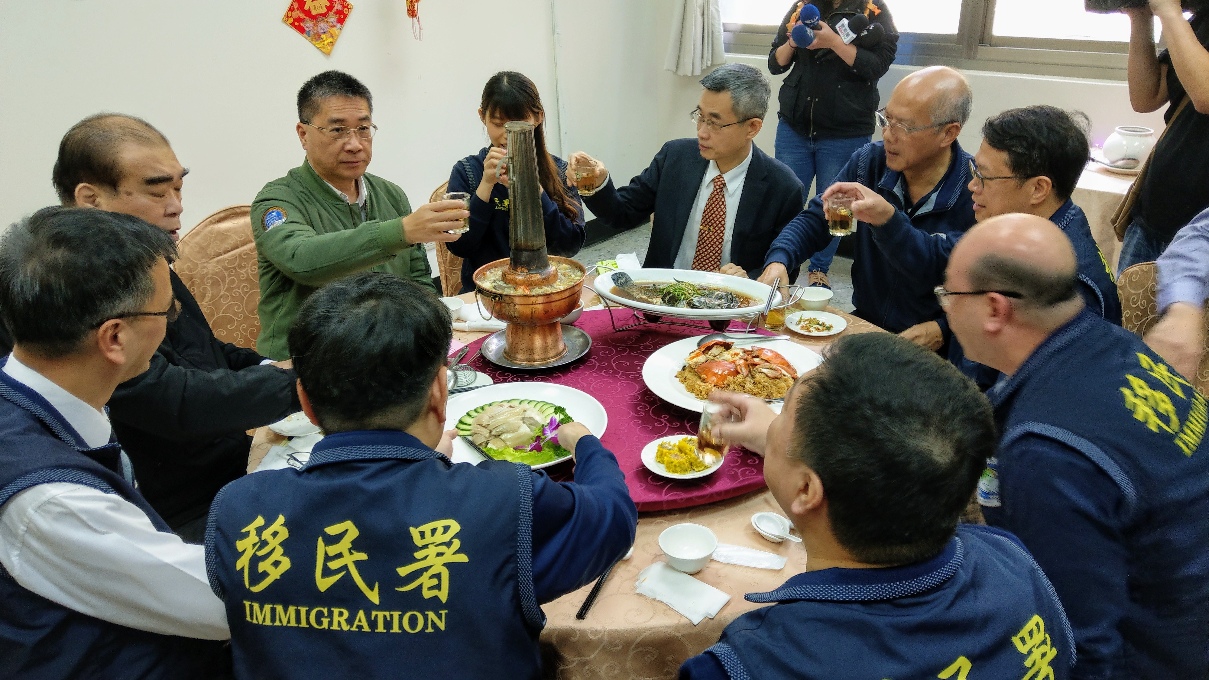 內政部部長徐國勇(著綠衣者)、移民署署長邱豐光(徐國勇左一)與移民署台北市專勤隊同仁圍爐。(歐陽夢萍 攝)