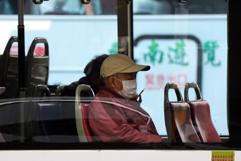 武漢肺炎疫情升溫，中央流行疫情指揮中心呼籲民眾在通風不良、有感染風險處應戴口罩。圖為民眾戴著口罩搭乘公車。(圖：中央社)