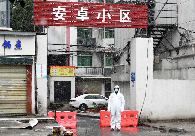 中國湖北省武漢市加強防疫，小區全面封管，違反規定就重罰。圖為武漢安卓小區入口，值守人員冒雪站崗。（中新社提供）
