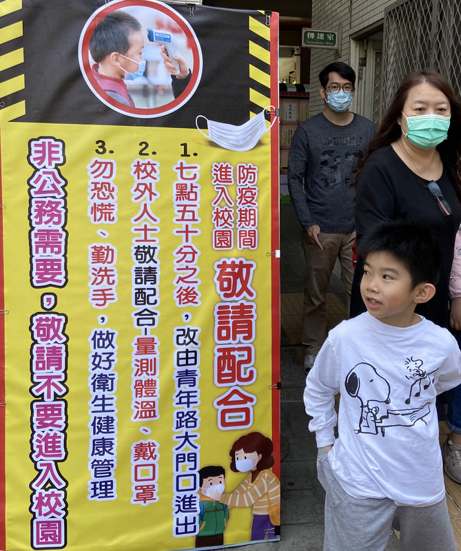 勞動部長許銘春21日在立法院表示，各級學校開學後，不排除有可能啟動第2波防疫照顧假。圖為高雄安親班業者安排小朋友們至國小校園戶外教學，校門口以明顯看板公告相關防疫措施。(圖/中央社)