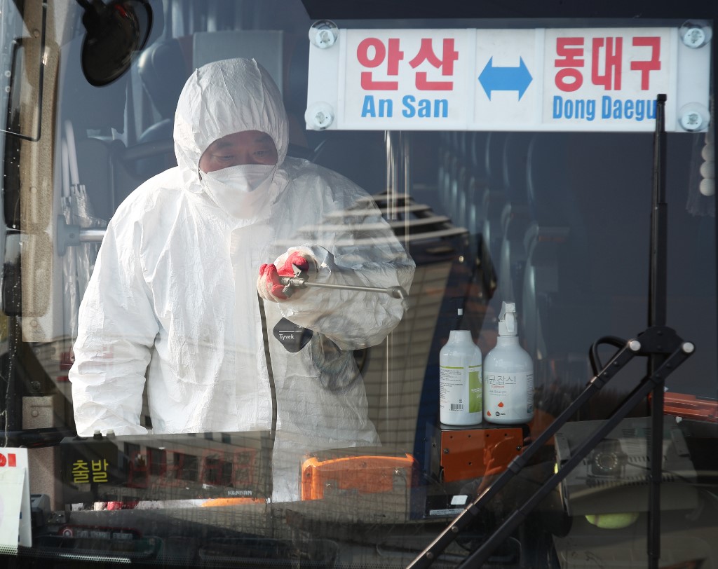 南韓的武漢肺炎疫情越來越嚴重，當地媒體擔心全球恐掀起「恐韓症」。圖為一名負責消毒的工作人員20日在京畿道安山市的一個公車總站，為一輛往返安山與大邱東區東大邱站的長途巴士噴灑消毒劑。（法新社）