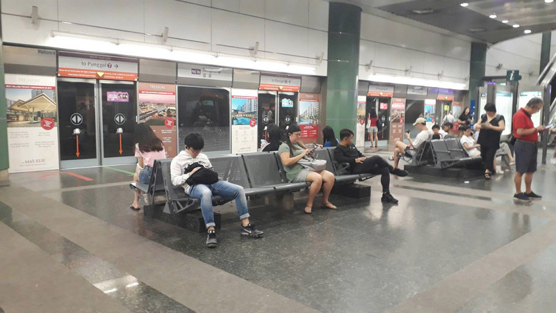 新加坡推動改變社交習慣的保持安全距離措施，地鐵站裡民眾在等候地鐵進站的座位區也相隔而坐，保持安全距離。(圖：中央社)