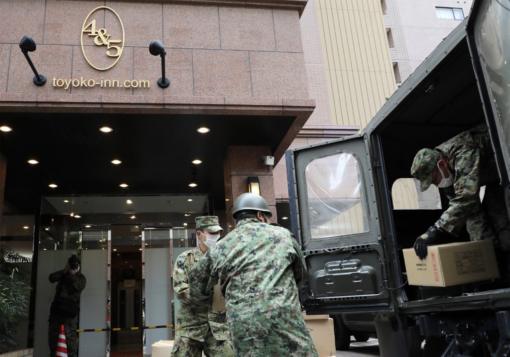 日本東京染疫輕症患者，將從醫院轉往飯店。圖為自衛隊士兵在指定飯店做準備。 (AFP)