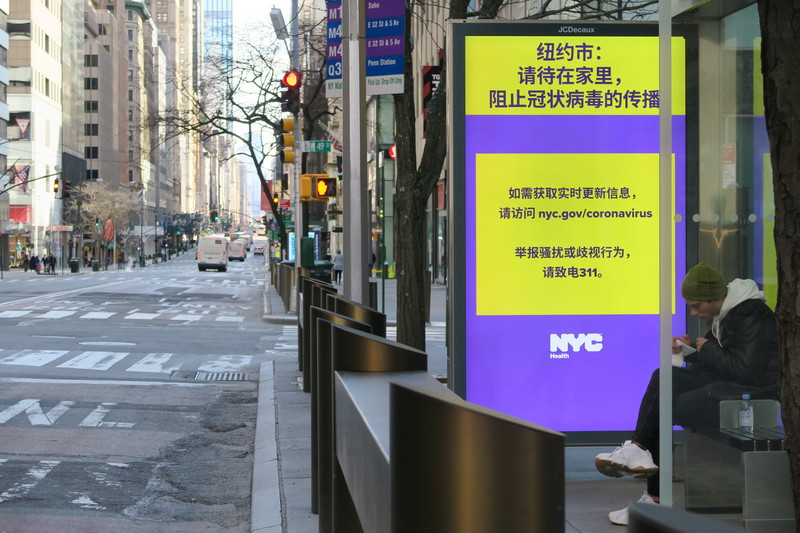 紐約市防止武漢肺炎疫情惡化，公車站廣告看板以簡體中文告示敦促市民盡量待在家，昔日車水馬龍的曼哈頓第五大道車流量銳減。(圖:中央社)