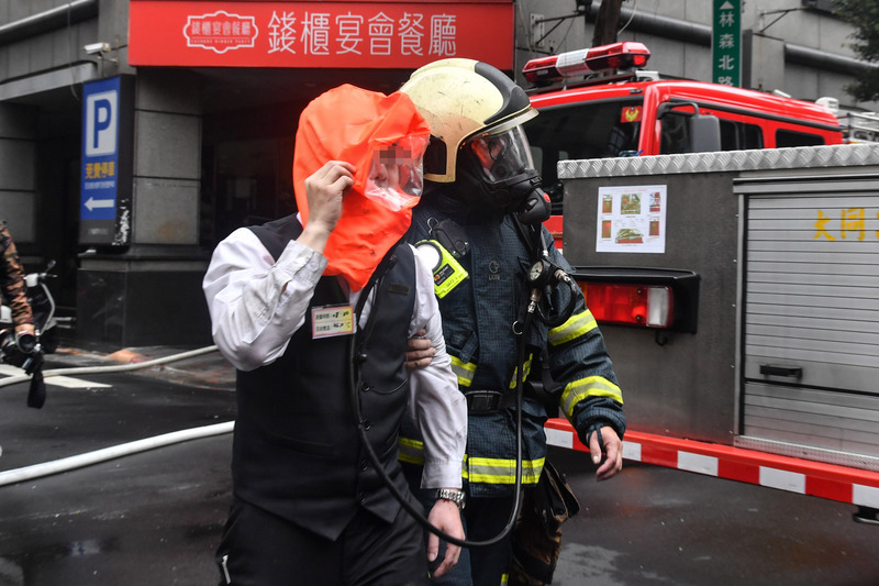 台北市錢櫃KTV26日傳出火警，現場火勢約於上午11時30分撲滅，消防人員協助民眾送醫。(圖: 中央社)
