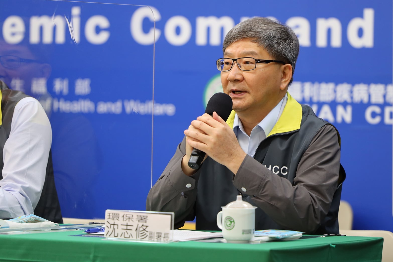 環保署副署長沈志修在中央流行疫情指揮中心上呼籲餐飲與民眾，清洗乾淨重複性餐具，少用免洗餐具，防疫同時善盡愛護地球責任。(指揮中心提供)