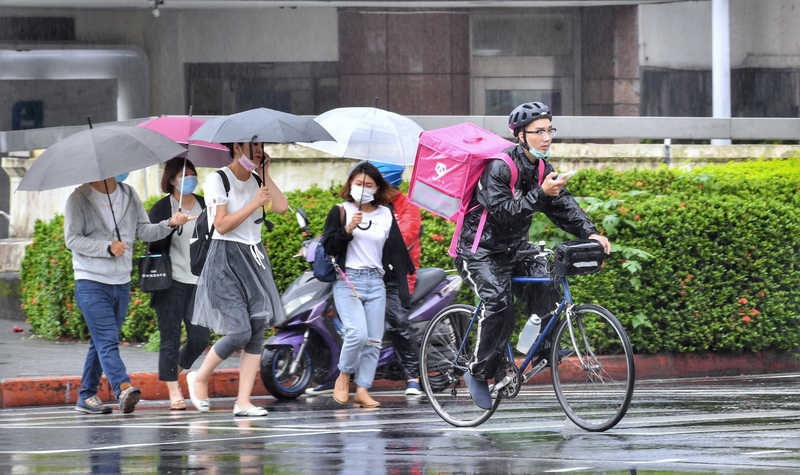 中央氣象局提醒民眾，這波雨還沒下完，下週還有一波雨彈。圖為台北街頭民眾撐傘避雨，外送員也在雨中送餐。(圖：中央社)