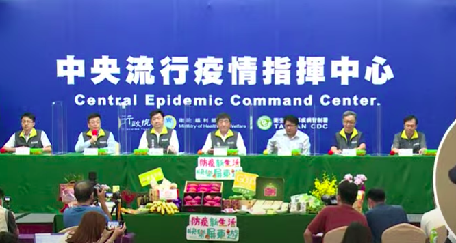 中央流行疫情指揮中心記者會今日移師墾丁召開，現場擺滿屏東濃特產品。圖取自直播畫面