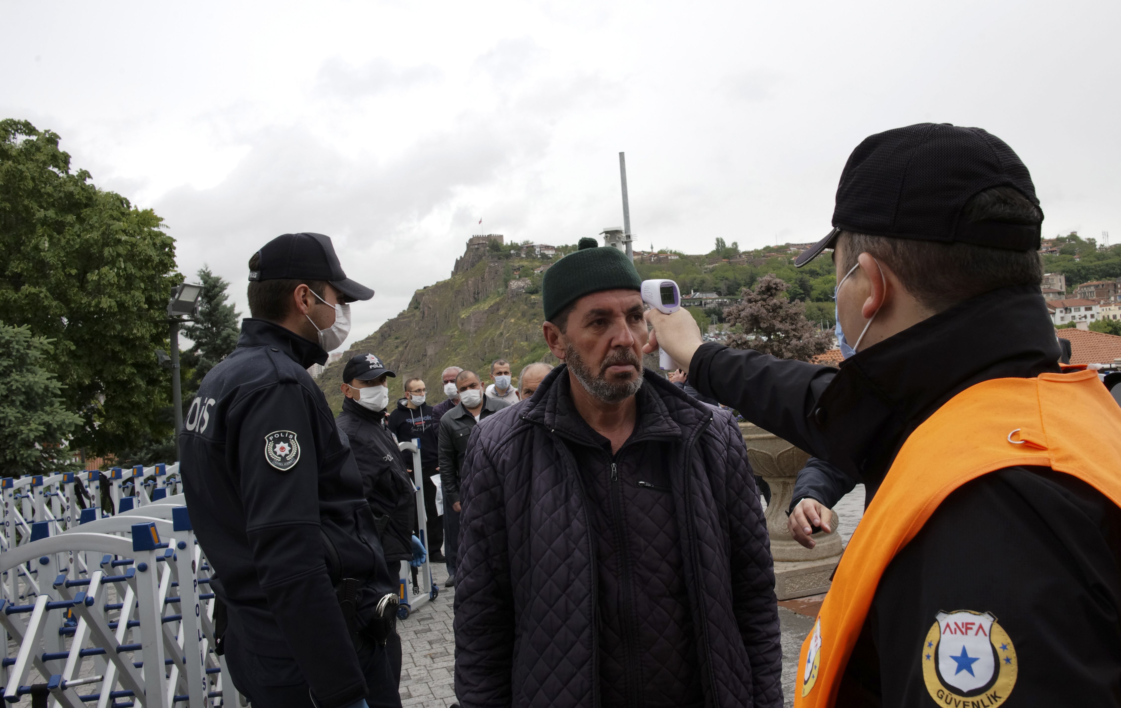 土耳其哈吉拜拉姆清真寺(Haci Bayram Mosque)入口午前出現排隊人潮，戴著口罩的民眾須測量體溫、乾洗手和領取清真寺提供的拋棄式祈禱墊，才能夠進入讓信徒進行聚禮的廣場。(美聯社/達志影像)