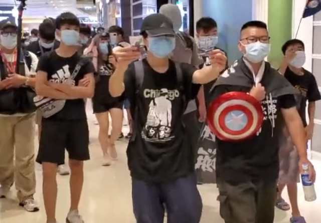 香港網友發起25日下午在元朗的一家商場舉行「端午節和你shop」活動，一些民眾在商場內高舉旗幟及高呼「五大訴求，缺一不可」等口號。(圖擷自YouTube)