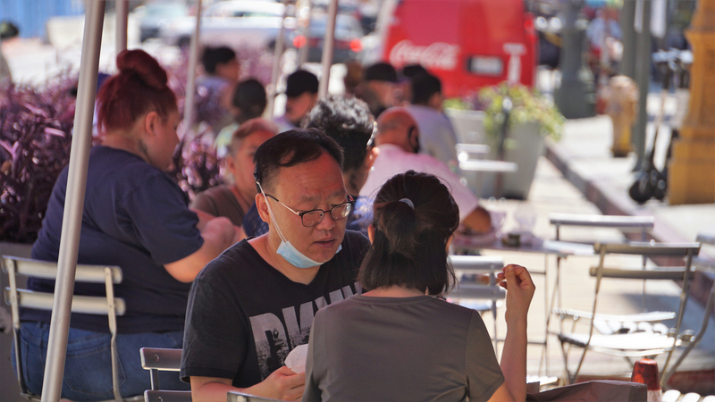 美國疫情未解、邁向重啟經濟之際，餐廳為了防疫在戶外設用餐區，顧客一邊用餐口罩仍然掛在下巴。(資料照片/中央社)