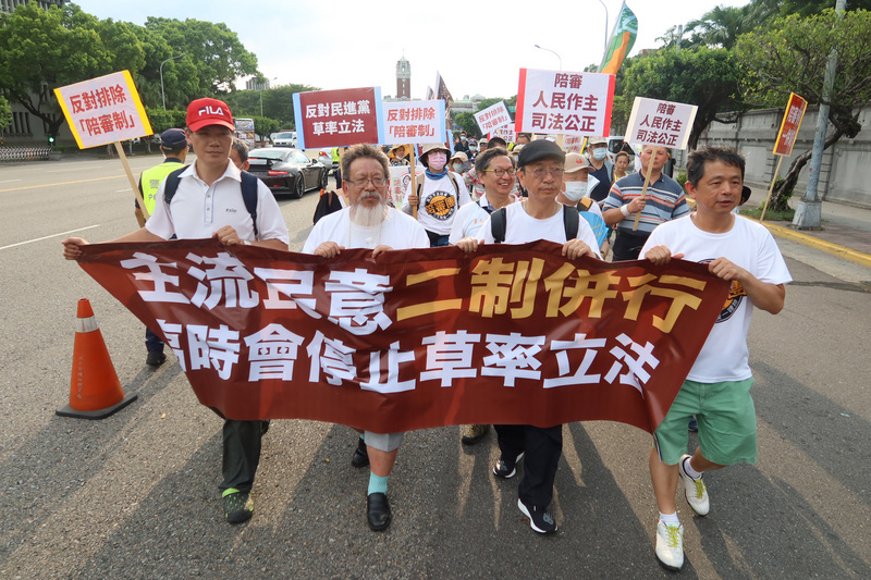 「陪審參審一併試行推動大聯盟」18日舉辦遊行活動，聯盟召集人林永頌（前右2）等人帶頭拉開「主流民意二制併行 臨時會停止草率立法」布條，以行動表達立場訴求。(圖：中央社)