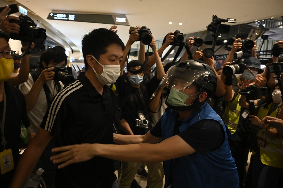香港立法會議員許智峯宣布流亡海外。圖為今年「721」白衣人襲擊事件一週年，群眾在元朗商場聚集；許智峯在警方封鎖線前用擴音器發言，被以涉嫌妨害公務為由拘捕。(資料照片／立場新聞提供)