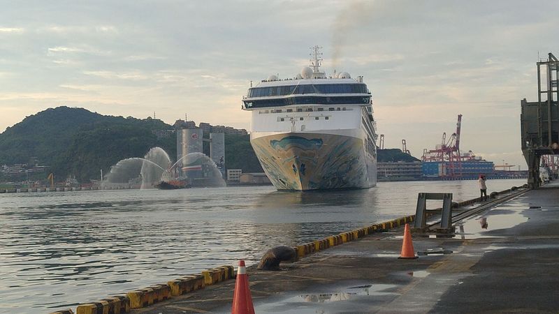 搭載1200名旅客的郵輪「探索夢號」26日晚間6時許伴隨夕陽餘暉，在拖船噴水歡送下緩緩駛離基隆港，展開台灣首發郵輪跳島遊程。(圖：中央社)