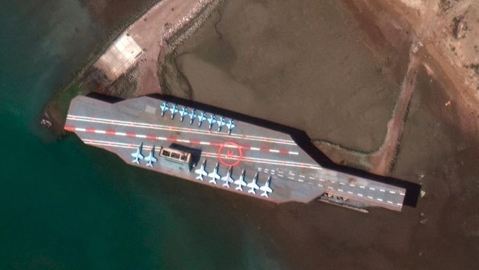 衛星照片顯示，伊朗已將一艘美國航空母艦的模型，放到戰略要地荷莫茲海峽入口處。(圖取自推特)