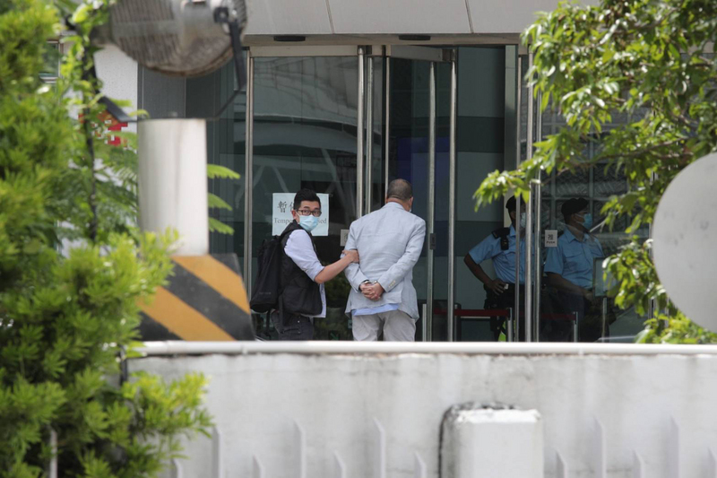 香港蘋果日報創辦人黎智英被扣上手銬，押送到蘋果日報大樓內協助查證。（圖:中央社）