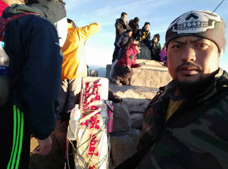 玉山主峰頂橫式英文石碑使用14年後，因損壞而功成身退，日前換上新石碑，執行作業的高山協作是41歲的松慶輝（前右），綽號黑熊，是信義鄉望鄉部落布農族人，他說，或許這輩子不會再有第2次機會背負主峰石碑，這次任務很有意義。（松慶輝提供）