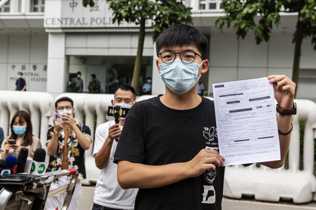 前香港眾志秘書長黃之鋒24日再被拘捕後獲釋，圖為黃之鋒離開中區警署前向媒體出示交保文件。 (AFP)