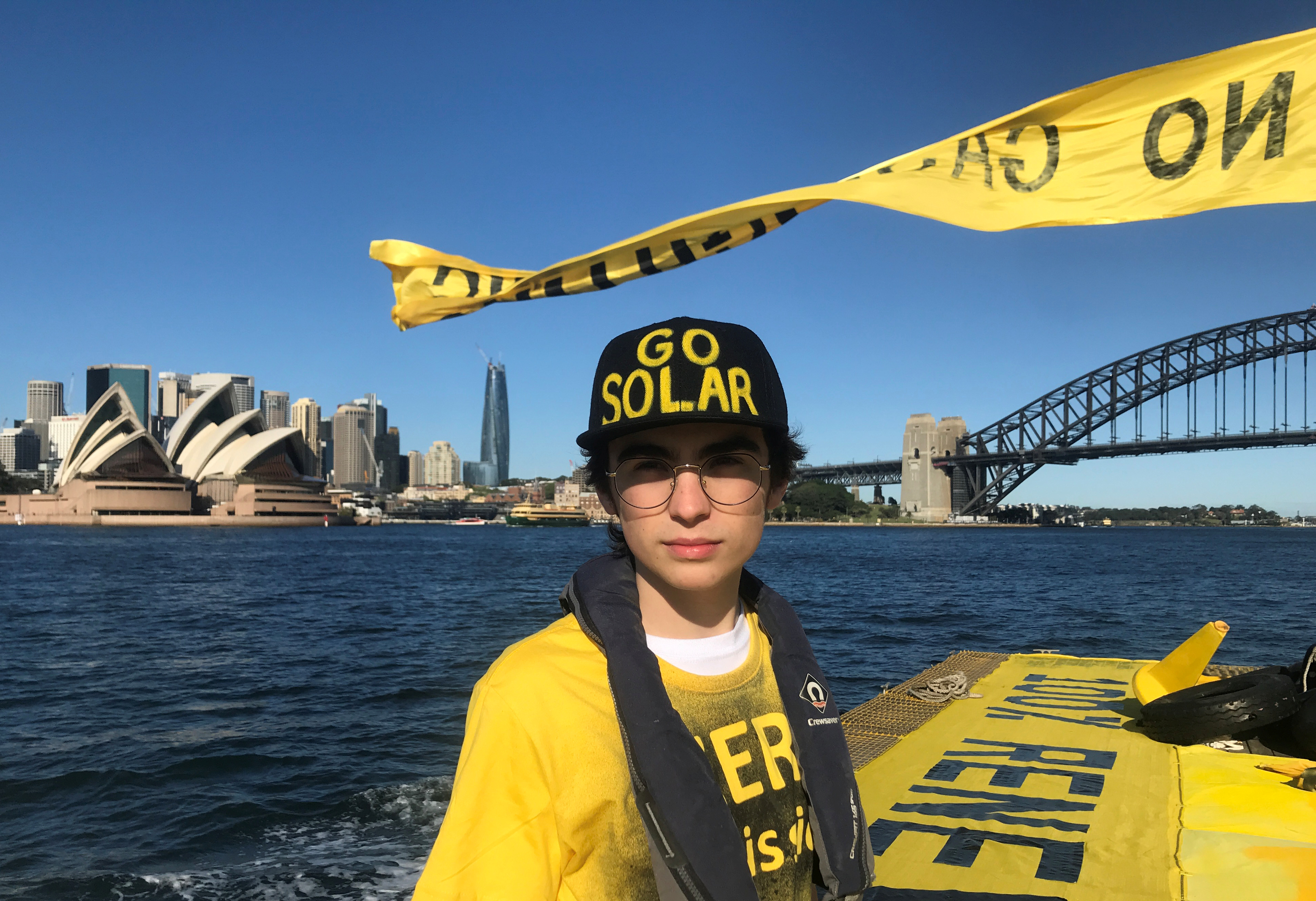15歲的澳洲學生海斯在行駛於雪梨港的一艘抗議船隻上，舉著巨型黃色標語，要求「無碳排」(No Gas)。(路透社/達志影像)