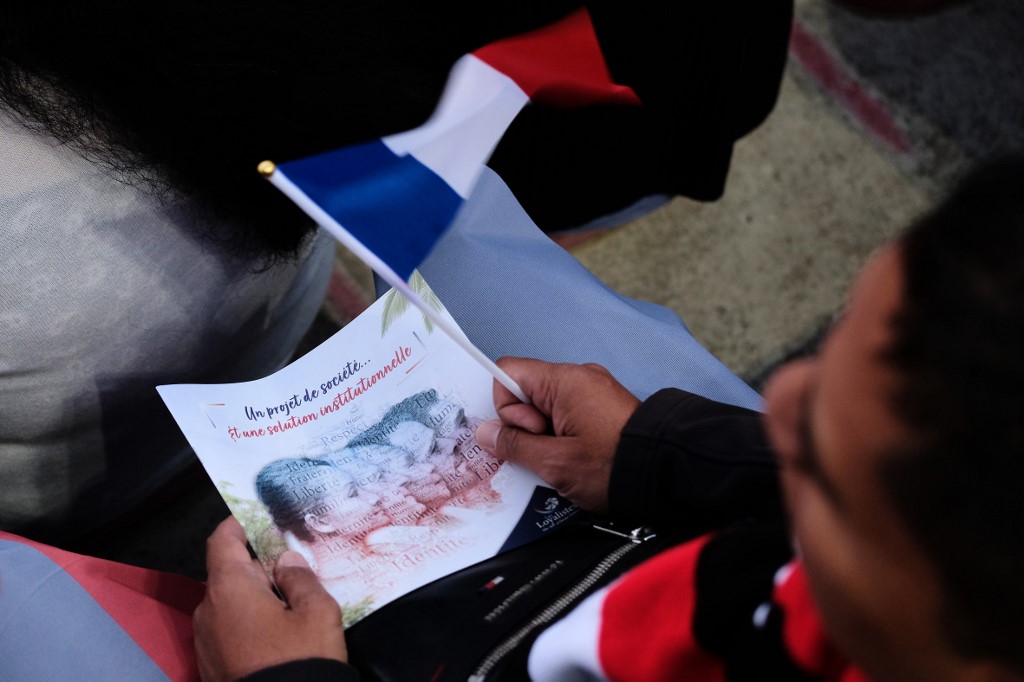 太平洋島嶼新喀里多尼亞(New Caledonia)4日將再度舉行公投，以決定是否終結法國屬地地位。圖為民眾拿著公投宣傳單。(法新社)