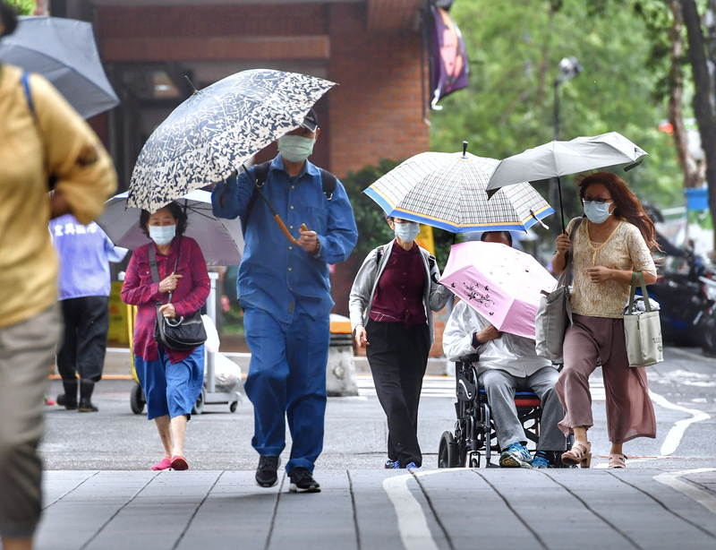 中央氣象局26日表示，27日起東北季風開始增強，北部、東半部未來一週高溫會逐漸下降，也會轉為有雨的天氣；另外在基隆北海岸、大台北山區、宜蘭等，可能會有局部大雨發生的機率。圖為台北市街頭民眾撐傘擋細雨。(圖：中央社)